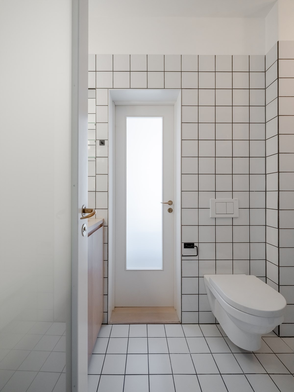 Badet er utstyrt med veggmontert toalett og dusjsone med innfellbar glassdører. Galleribilde
