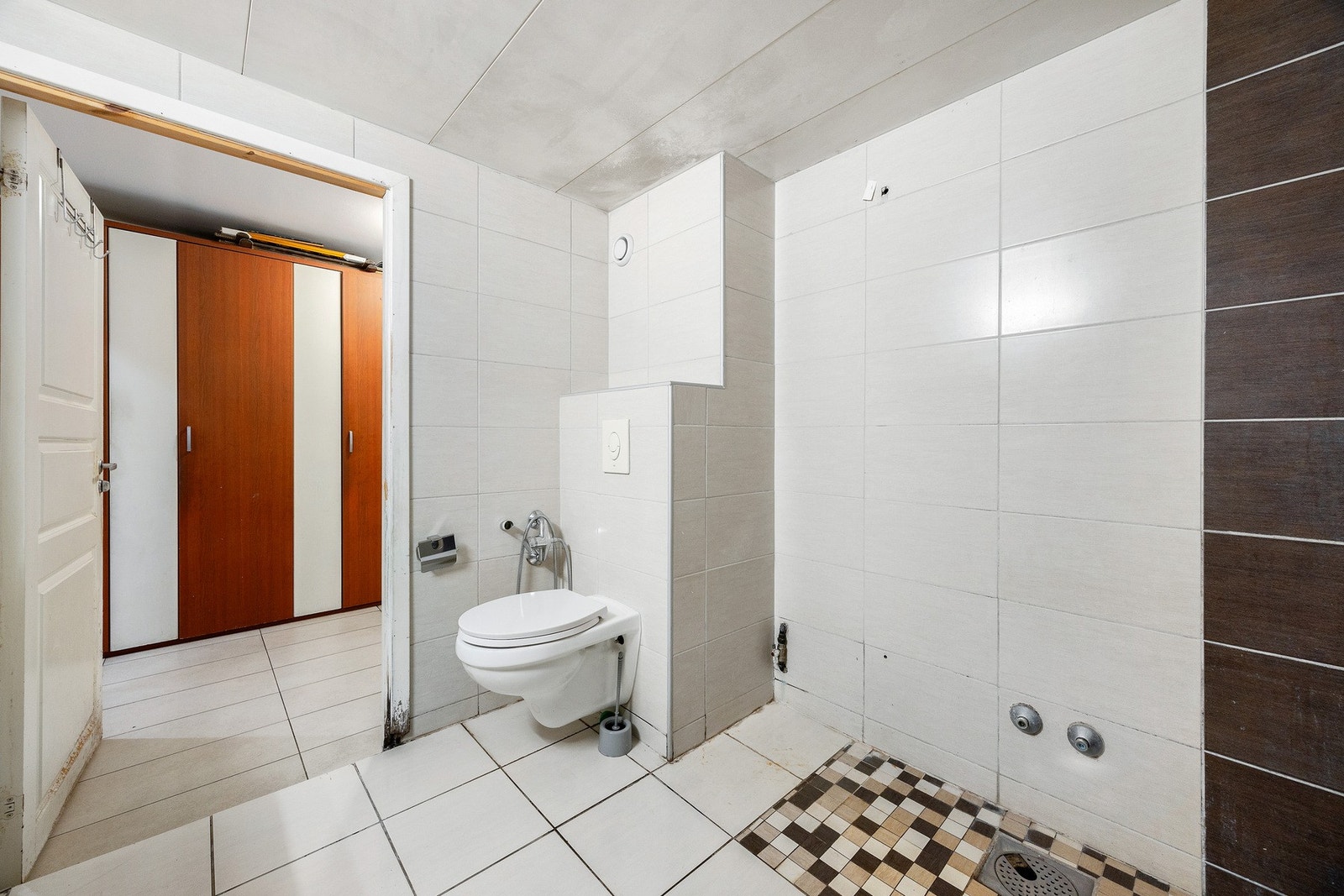 Badet er innredet med plassbygget servantbenk, vegghengt speil, vegghengt totalett og opplegg for badekar (badekar og blandebatteri er fjernet). Galleribilde