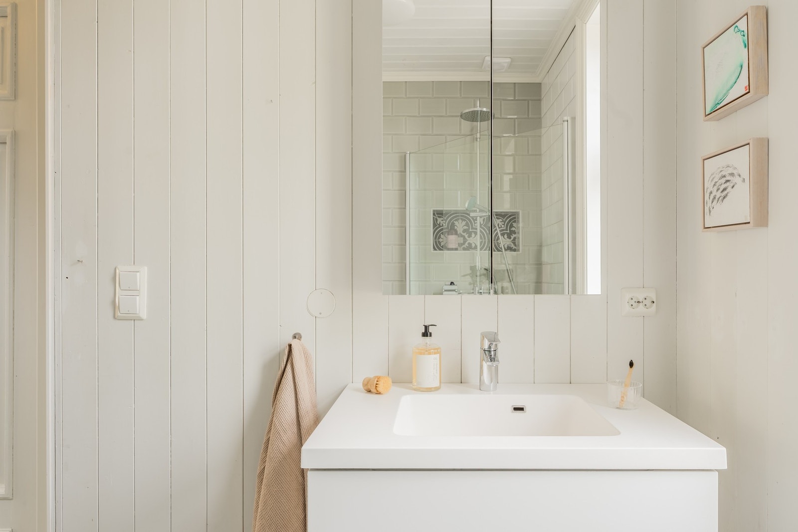 Badet er innredet med vegghengt toalett, servant med innredning og dusj med glassdører. Galleribilde