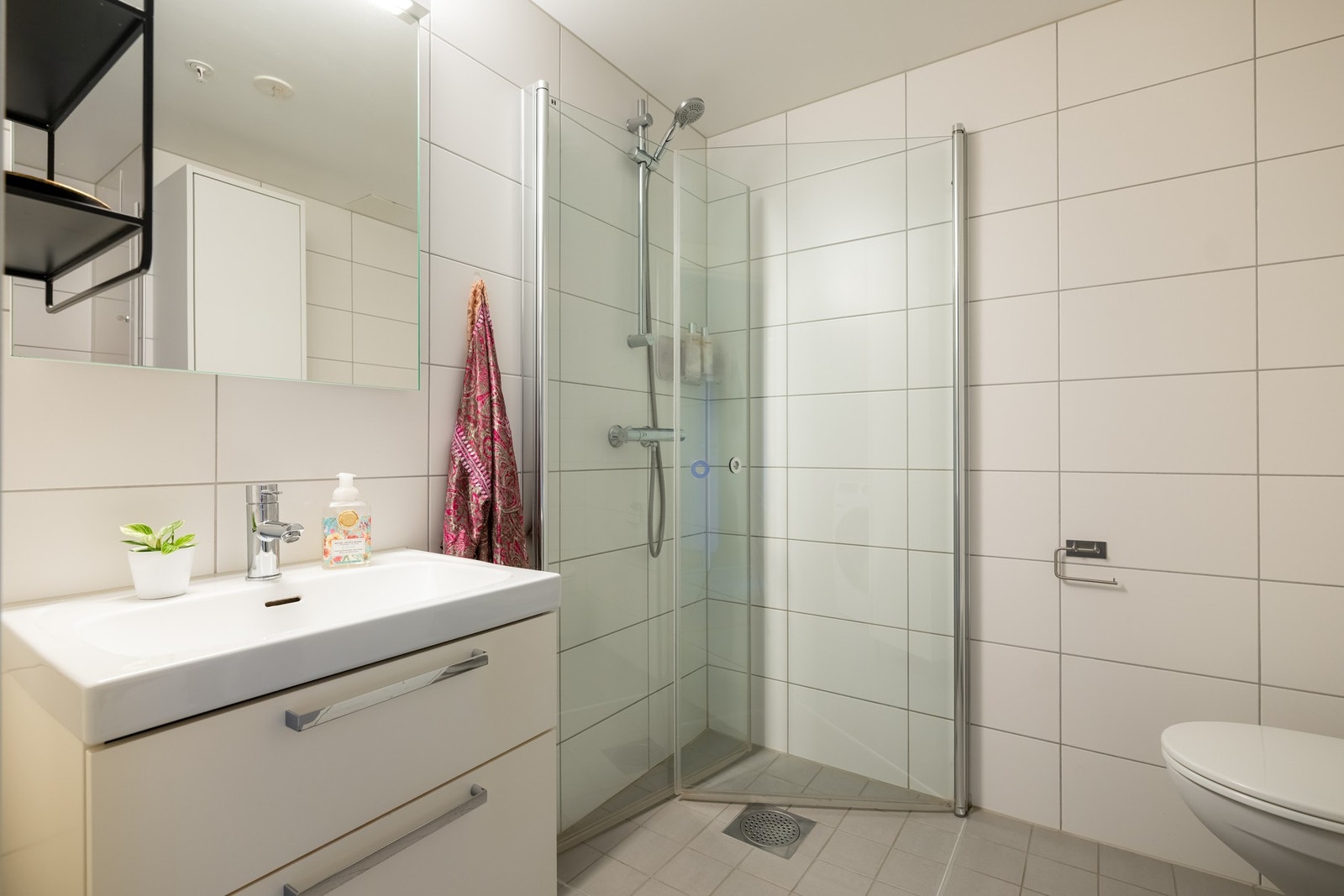 Lyst flislagt baderom med varme i gulv. Badet har opplegg for vaskemaskin. Galleribilde