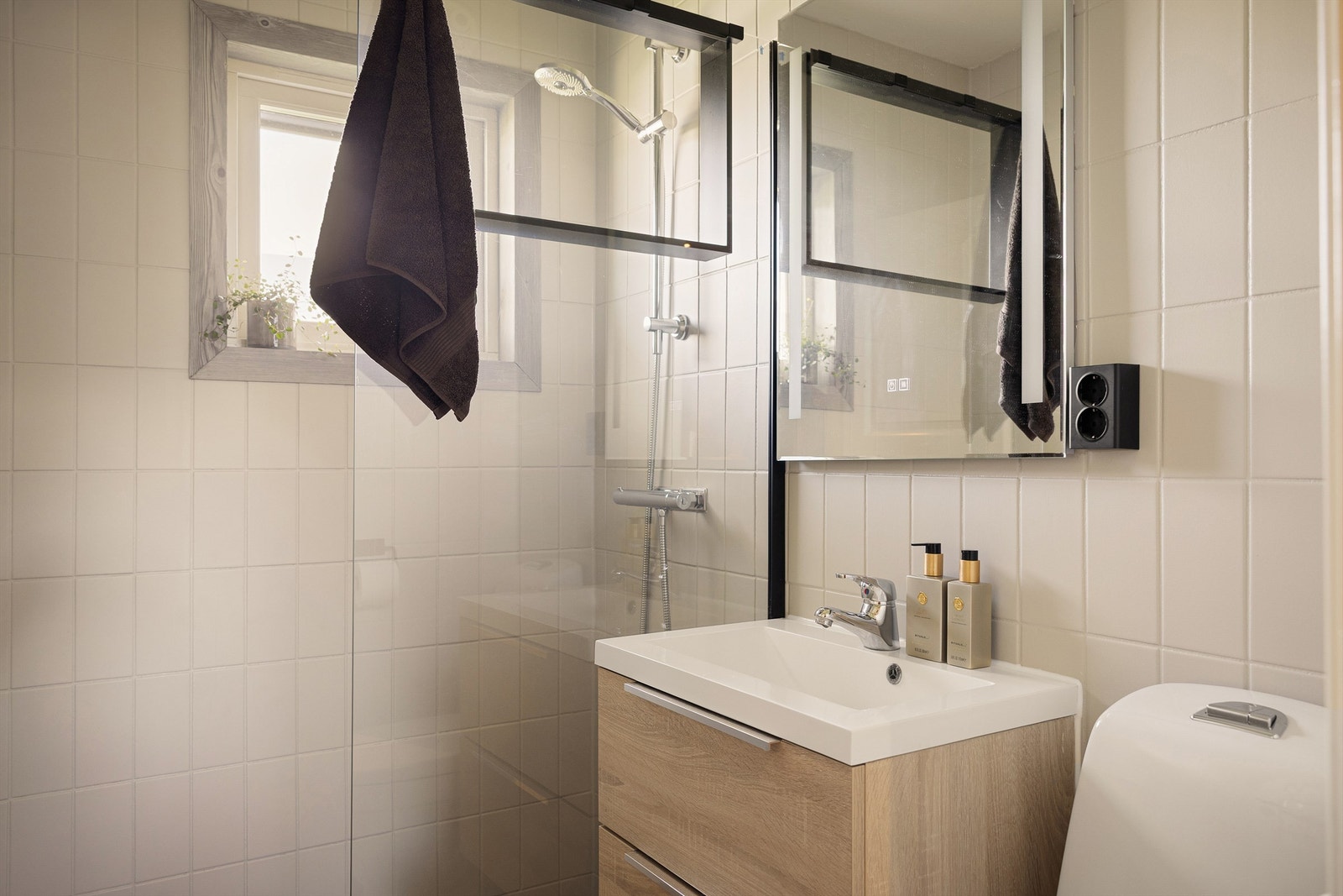 Badet har elektrisk gulvvarme, flislagte overflater og et praktisk dusjhjørne med glassfelt. Galleribilde