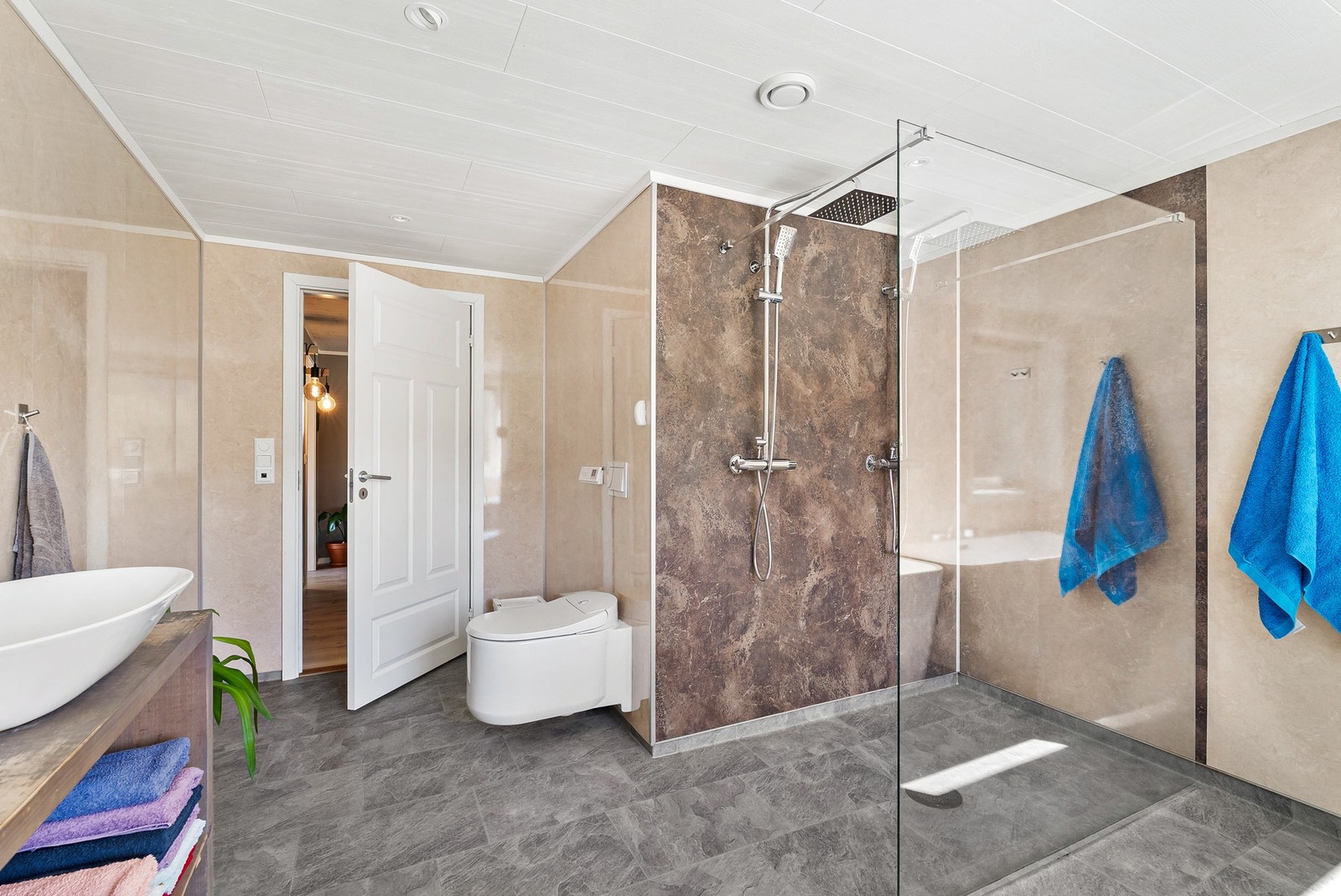 Badet har vinylbelegg på gulv med fall til to sluk, og vegghengt toalett. Galleribilde