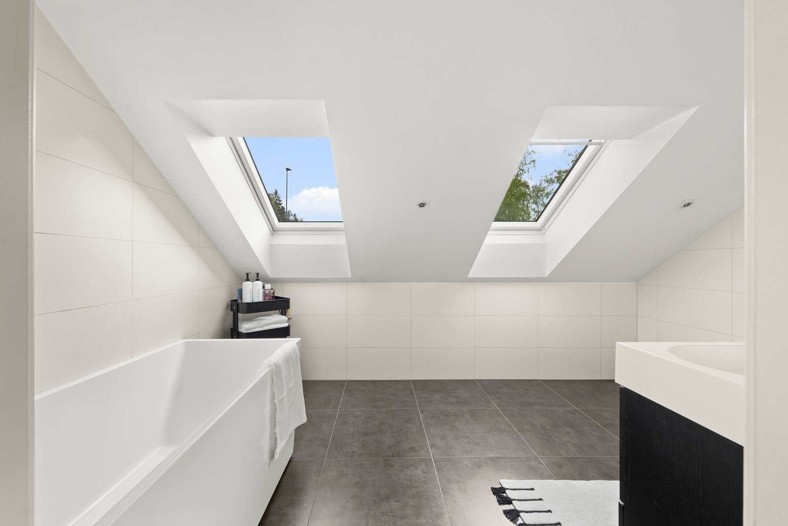 Badet fremstår moderne med helflisede overflater og stilren innredning. Galleribilde