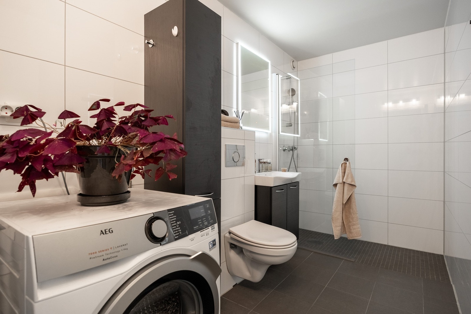 Badet er utstyrt med servant, klosett, dusj på gulv og opplegg for vaskemaskin. Galleribilde