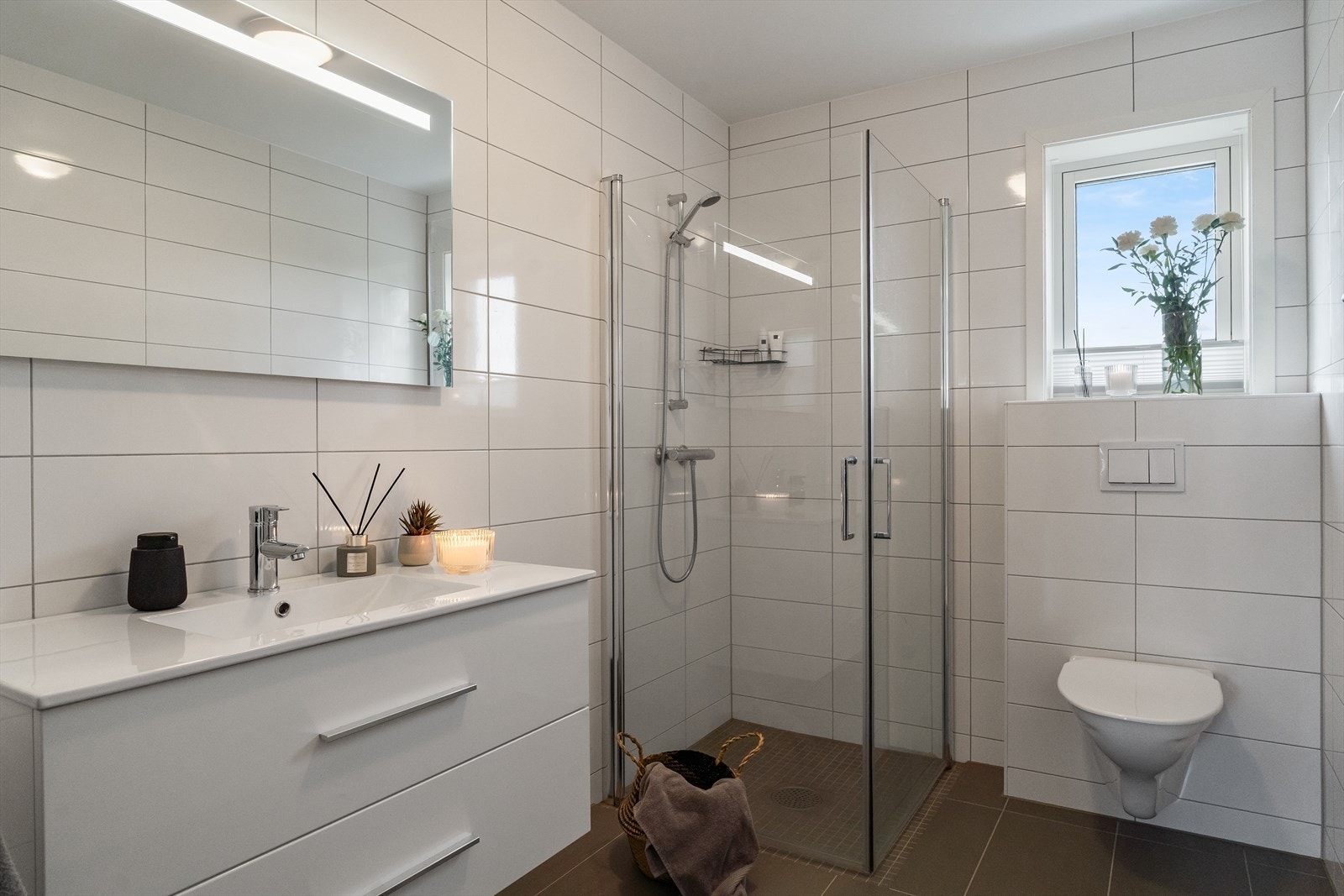 Lekkert, helfliset bad i 1. etasje med grå fliser på gulv og hvite fliser på vegg. Galleribilde