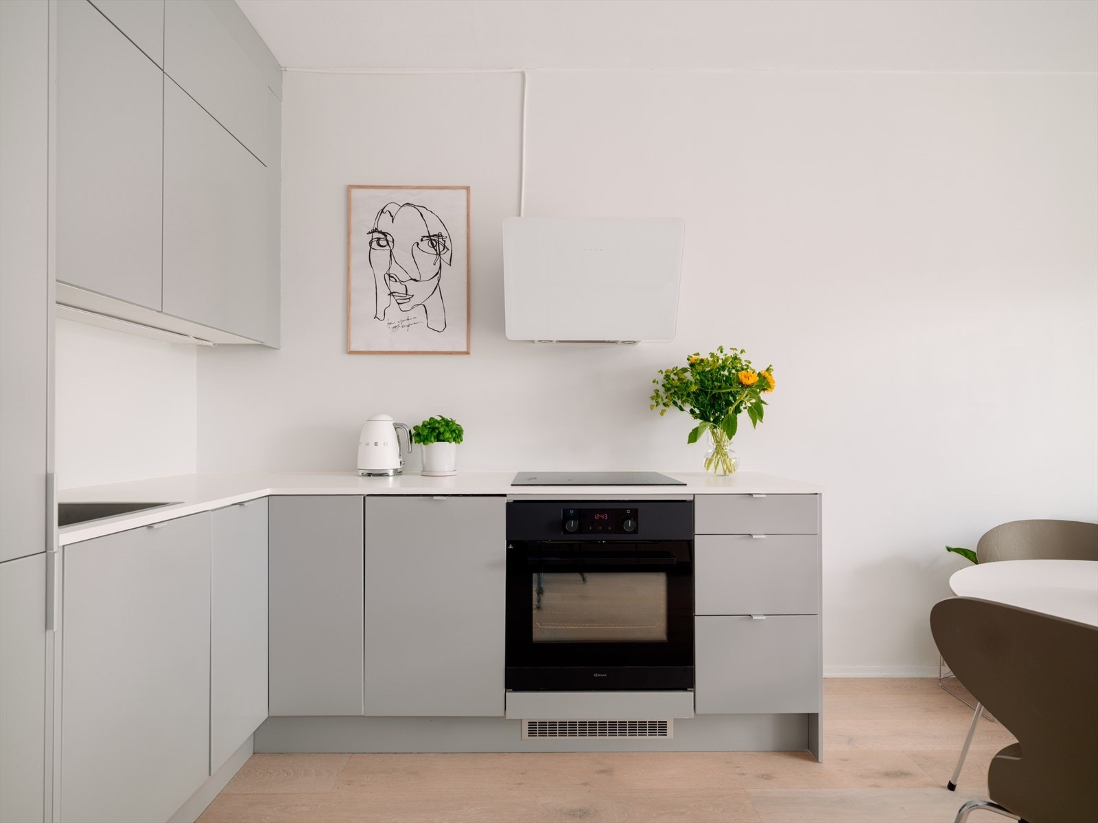 Kjøkkenet har et moderne og stilrent uttrykk med glatte, folierte fronter, benkeplate og nedfelt kum i rustfritt stål. Galleribilde