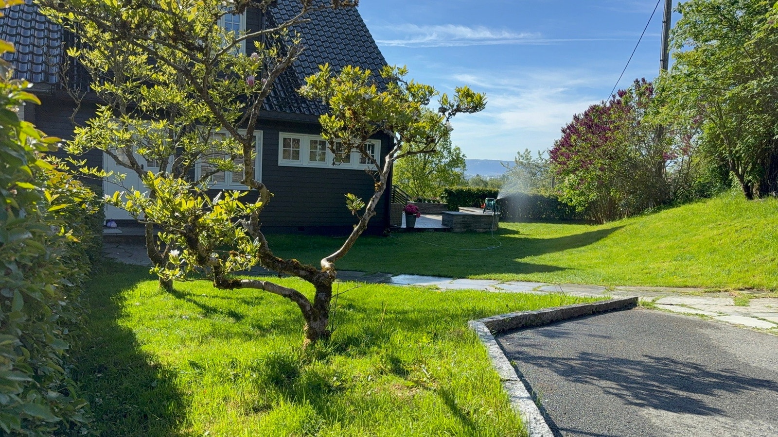 Tomten er pent opparbeidet med hellelagte gangsoner, skjermende beplantning og flere naturlige oppholdssoner. Galleribilde