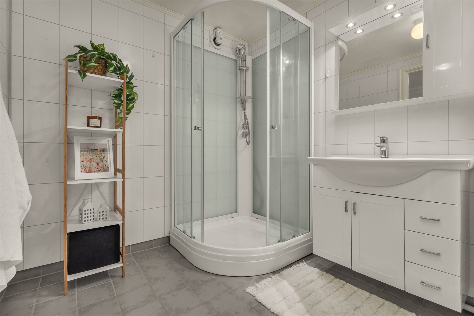 Badet har en funksjonell planløsning med dusjkabinett, servantinnredning og god gulvplass Galleribilde