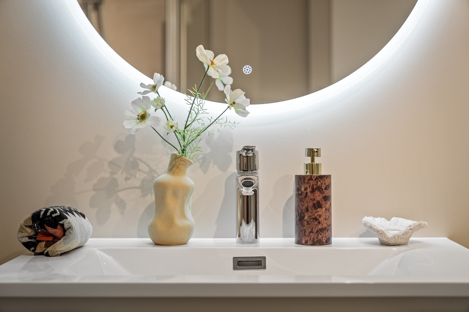Badet har moderne baderomsinnredning med plass til oppbevaring og speil med innfelt belysning Galleribilde
