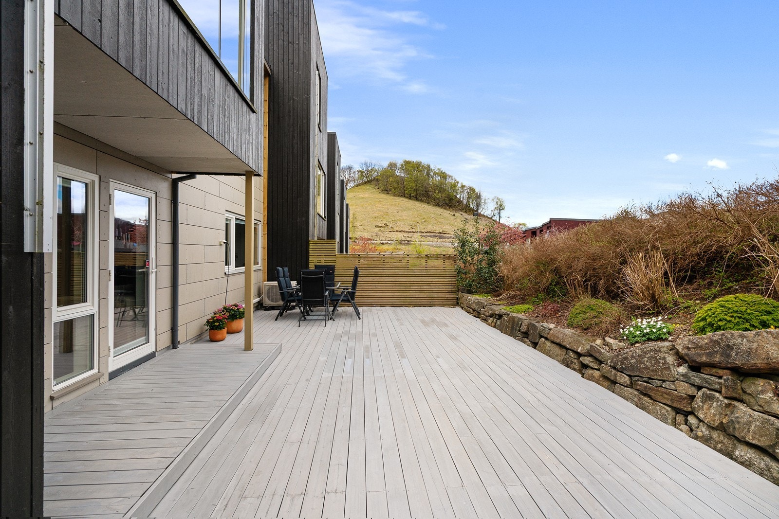 Uteområdet har en stor terrasse med lødd stein, samt blomsterbed og hekk. Galleribilde