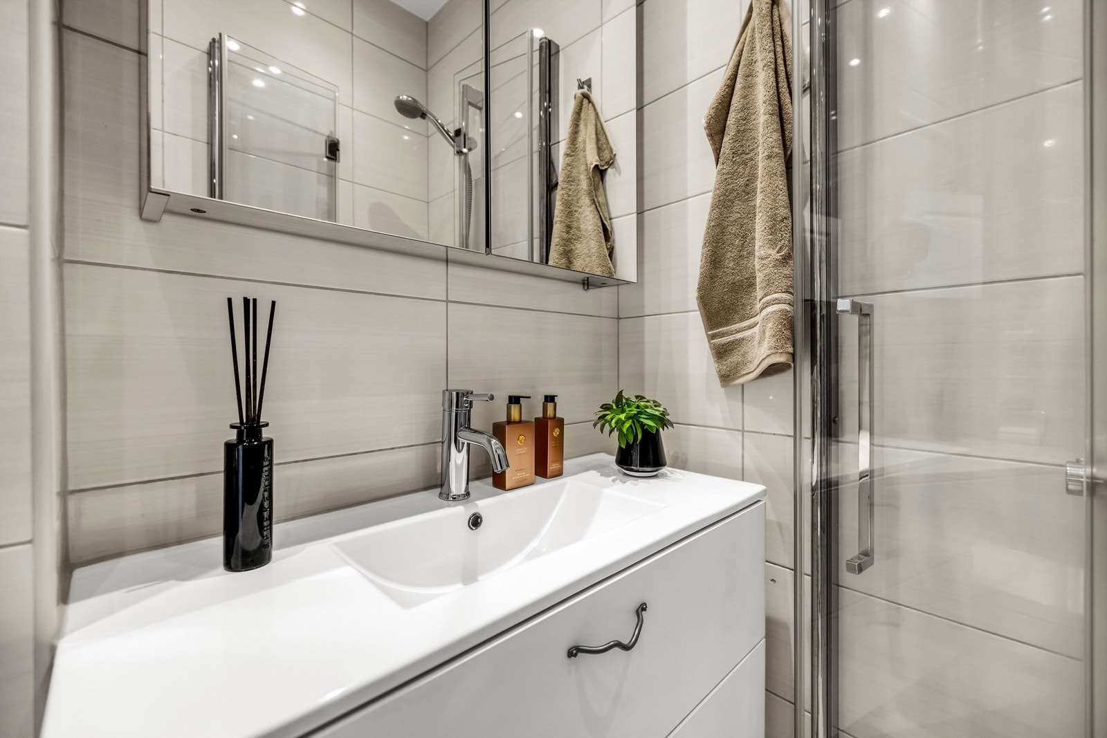 Badet er innredet med vegghengt servant med plass til oppbevaring i skuffer og speilskap over servant som gir ekstra lagringsplass. Galleribilde