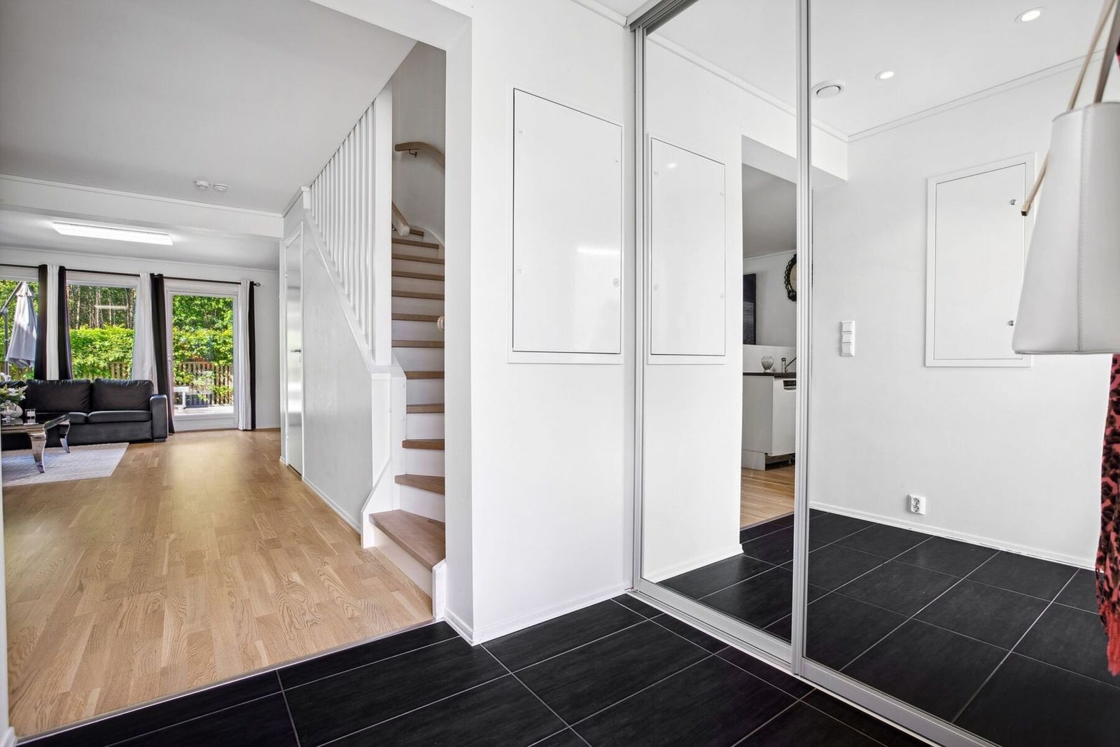 Entréen har sorte fliser på gulv, vannbåren gulvvarme, glatte lysmalte overflater, skjult elektrisk anlegg og downlights i himlingen. Galleribilde