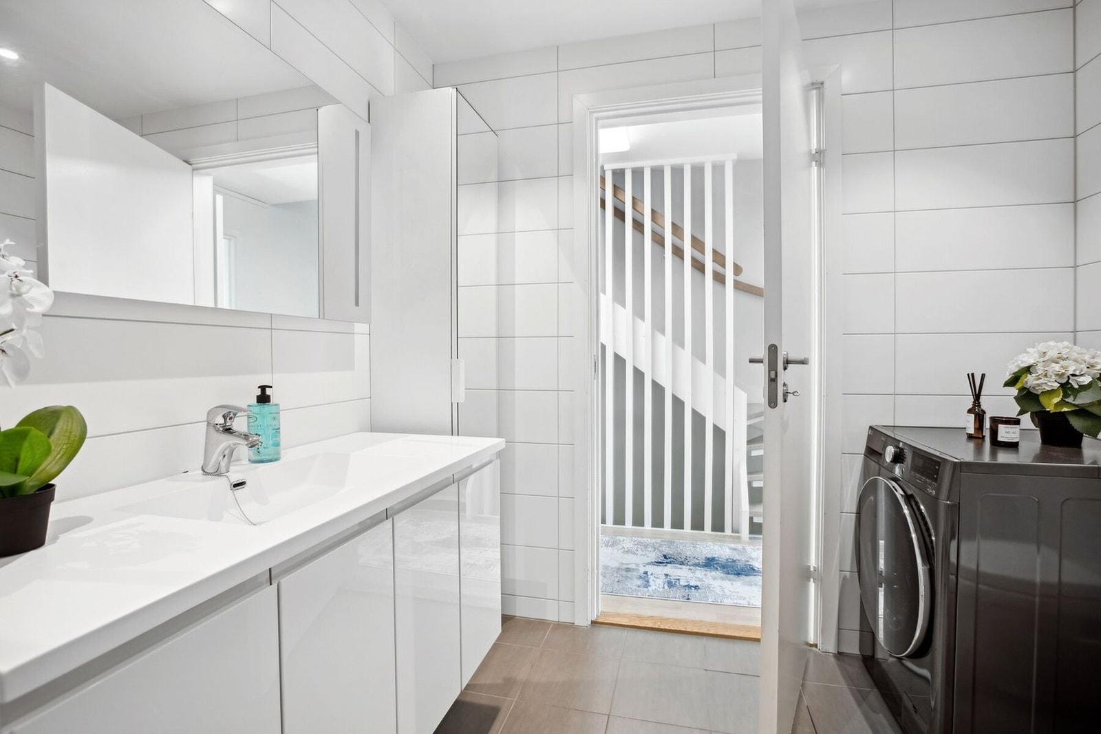 God oppbevaringsplass i lys baderomsinnredning med heldekkende servant, samt ekstra høyskap med speildør ved siden av. I hjørnet er det plass og opplegg for vaskemaskin og tørketrommel over om ønskelig. Galleribilde