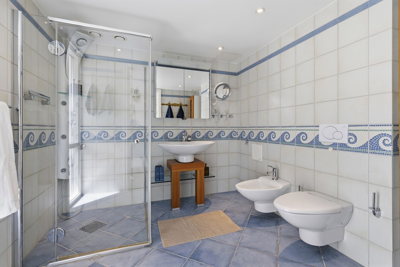 Bad 4 innredet med veggmontert servant med blandebatteri. Dusjhjørne med innfellbare dusjdører. Veggmontert toalett og bidet Galleribilde