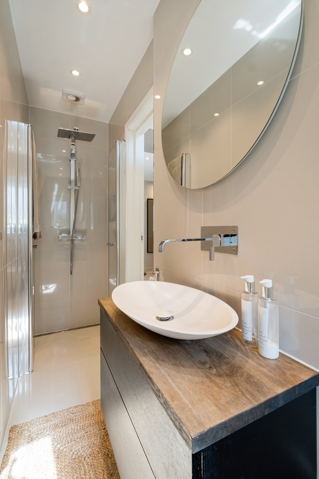 Badet er innredet med servant på heldekkende benkeplate, vegghengt toalett og dusjhjørne med glassvegger. Galleribilde