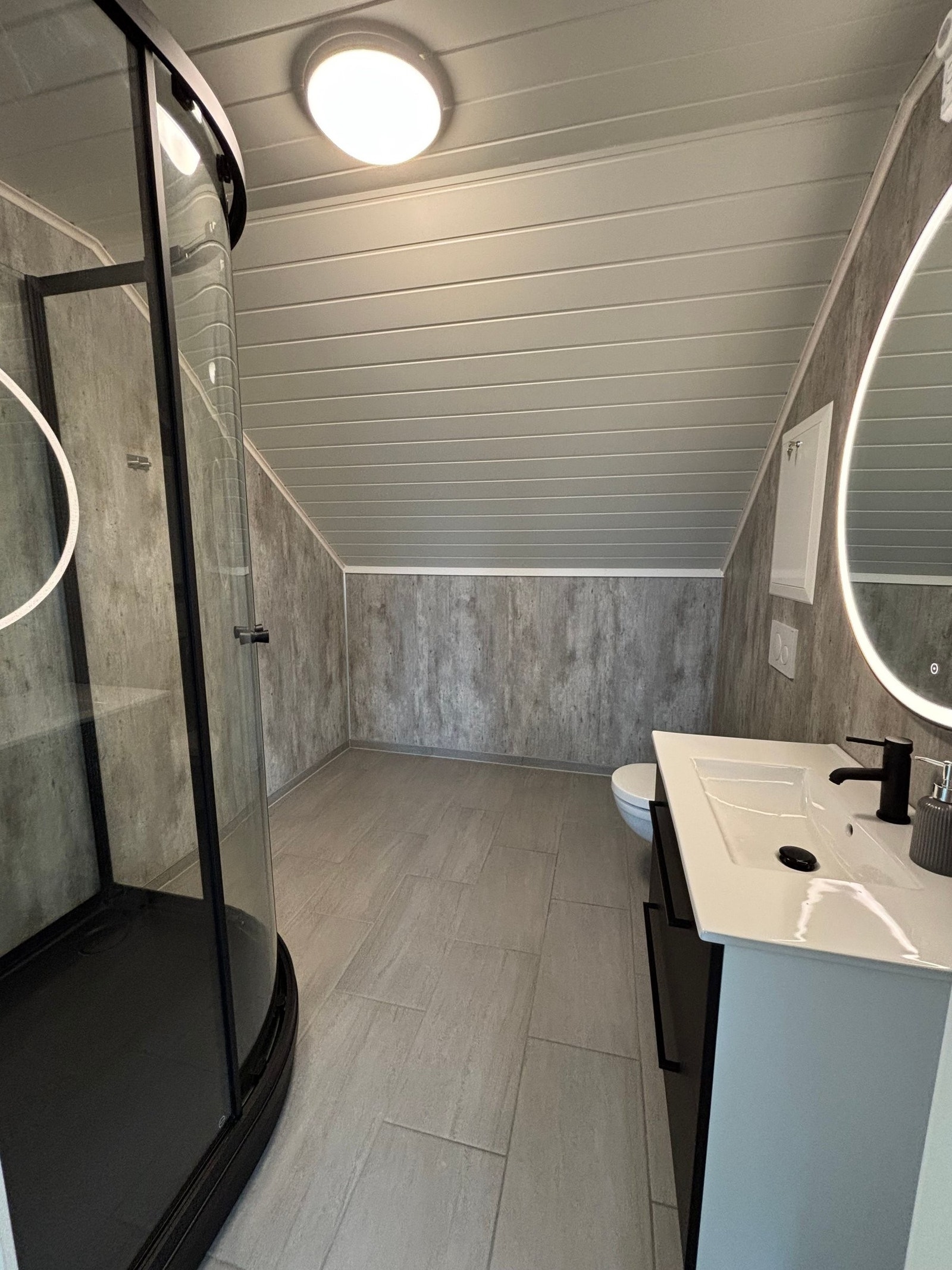 Badet er stort og lyst med vegghengt toalett og dusjkabinett Galleribilde