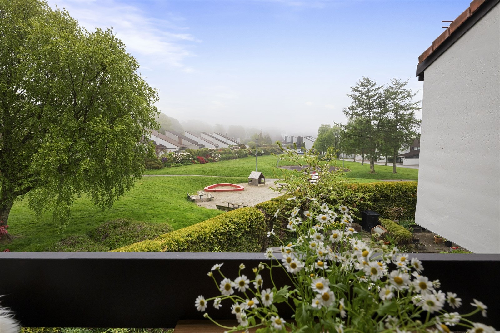 Fra balkongen ser man ut over borettslagets lekeplass og grønne fellesarealer. Galleribilde