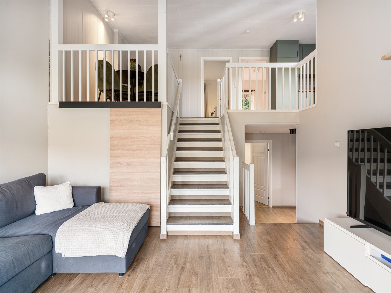 Den åpne, malte tretrappen binder etasjene sammen og bidrar til en luftig romfølelse. Skyvedør inn til lagringsplass. Galleribilde