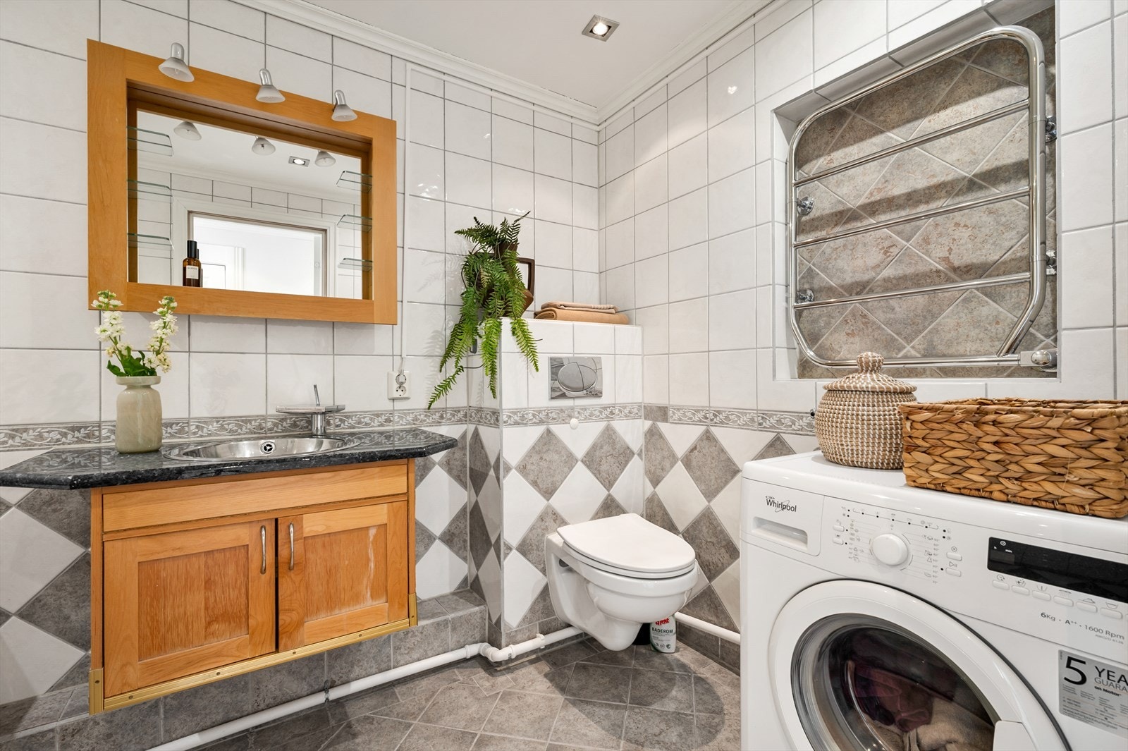 Badet har flissatte vegger og slette, malte himlingsflater med downlights. Rommet er innredet med en servantseksjon med skapdører, steinplate med nedfelt servant i rustfritt stål. elektrisk håndkletørker og opplegg for vaskemaskin. Galleribilde