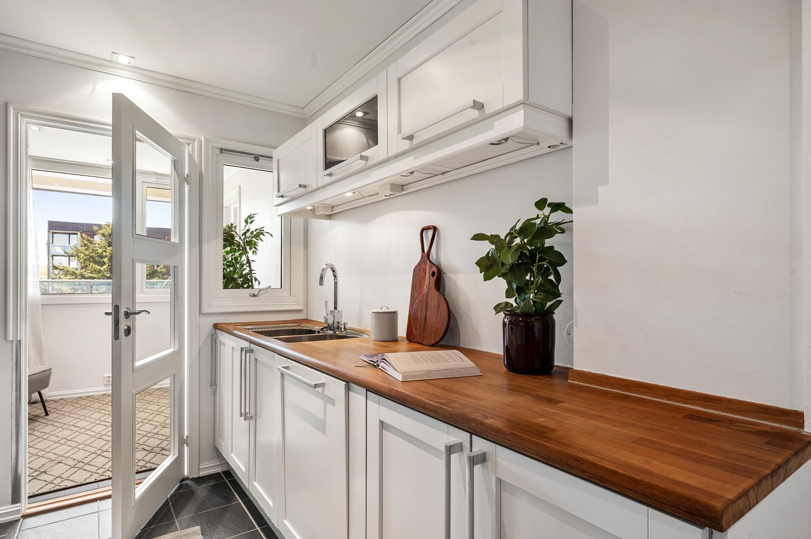 Kjøkkenet er utstyrt med nedfelt kum i rustfritt stål, ett-greps blandebatteri, glassplate på vegg ved stekesone og halogen downlights under overskap. Galleribilde
