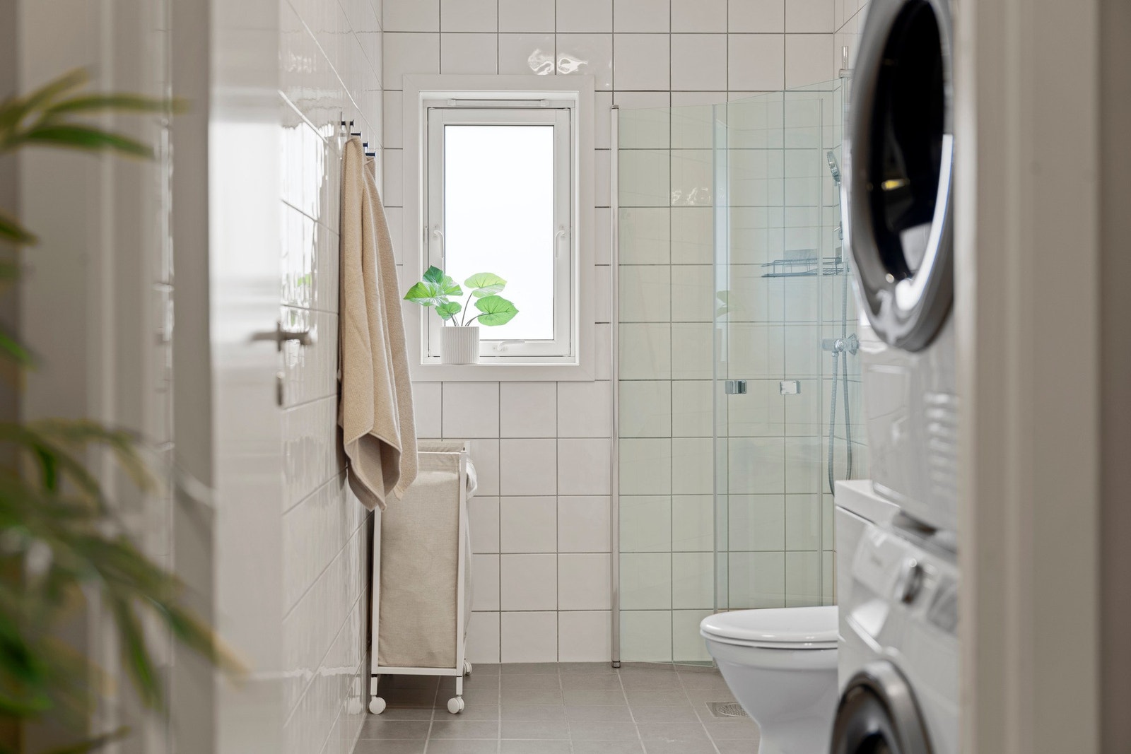 Romslig og delikat kombinert bad og vaskerom med moderne uttrykk og flislagte overflater på både gulv og vegger. Badet fremstår lyst og innbydende med en praktisk planløsning som gir god utnyttelse av rommet. Innredningen består av servant med tilhørende Galleribilde