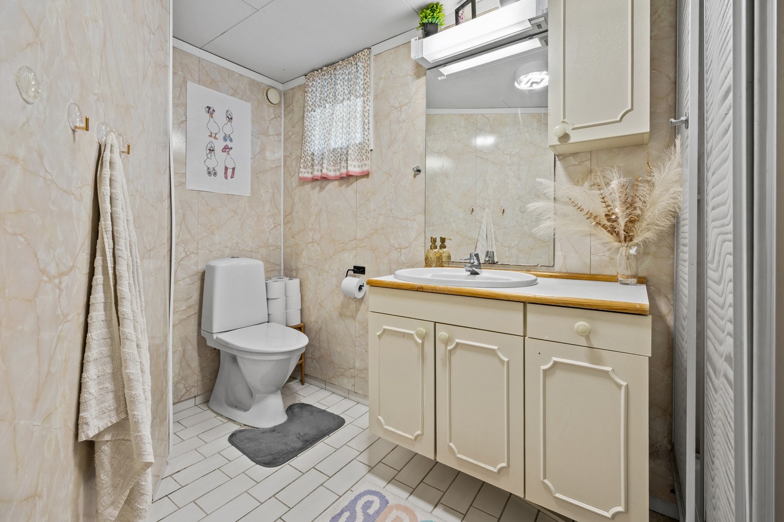 Eldre bad i boligens kjeller, vurdert til å være fra perioden mellom 1980-1990. Badet har flislagt gulv med gulvvarme og veggflater med baderomsplater. Galleribilde