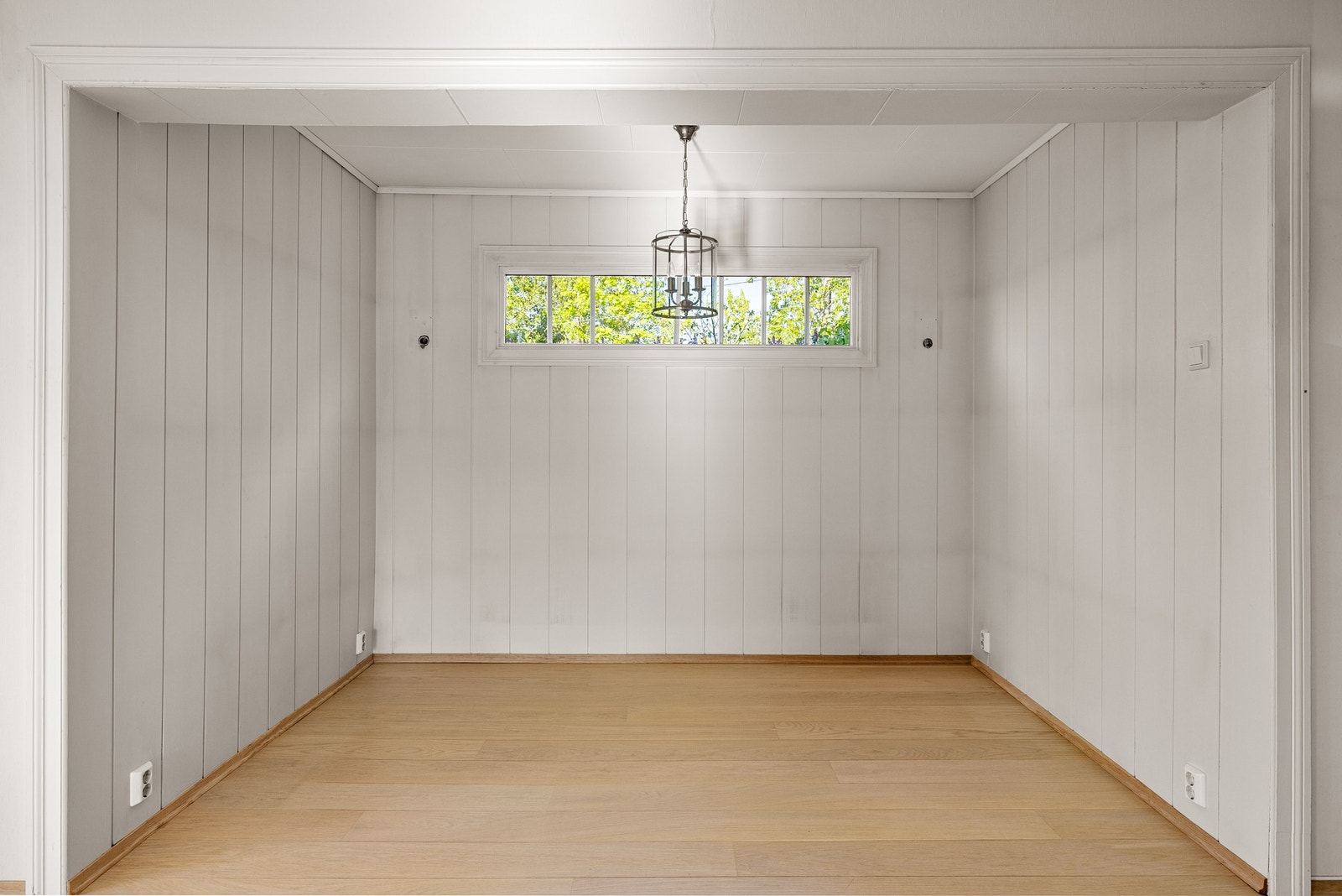 Stuen har pen enstavs parkett på gulv og lysmalt panel på veggene. Galleribilde
