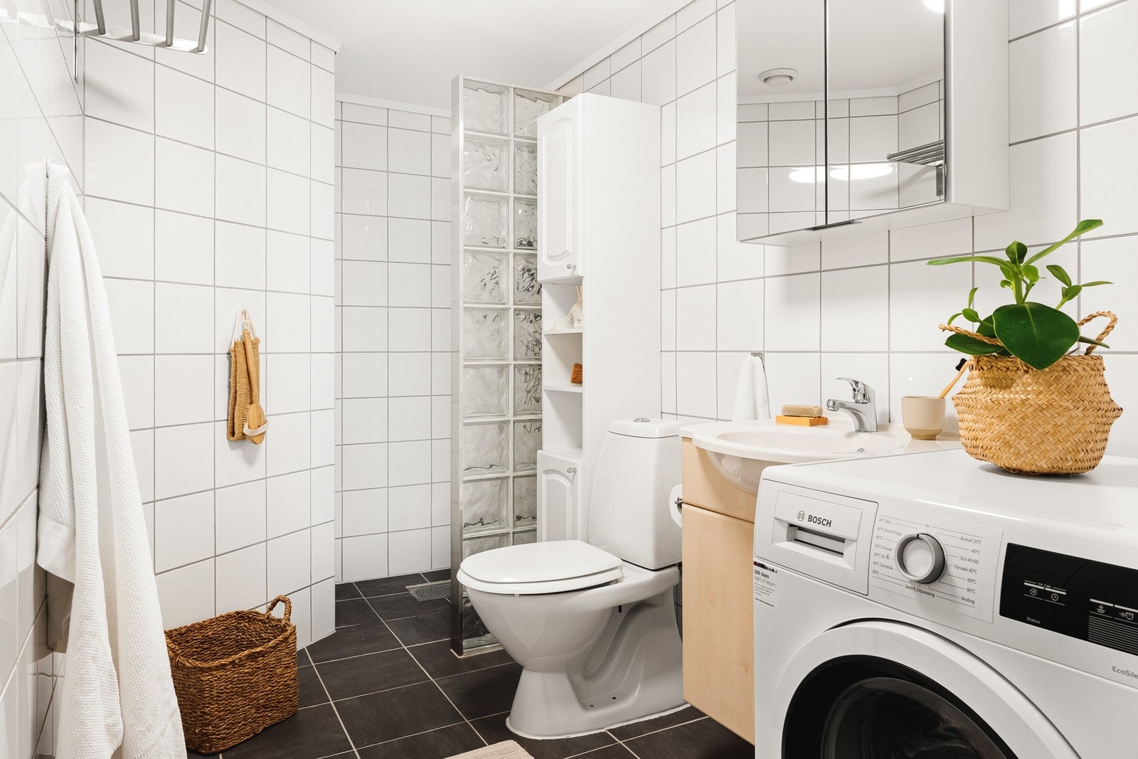 Badet er helfliset og innredet med dusjhjørne, servant med møblement, toalett og opplegg for vaskemaskin. Galleribilde