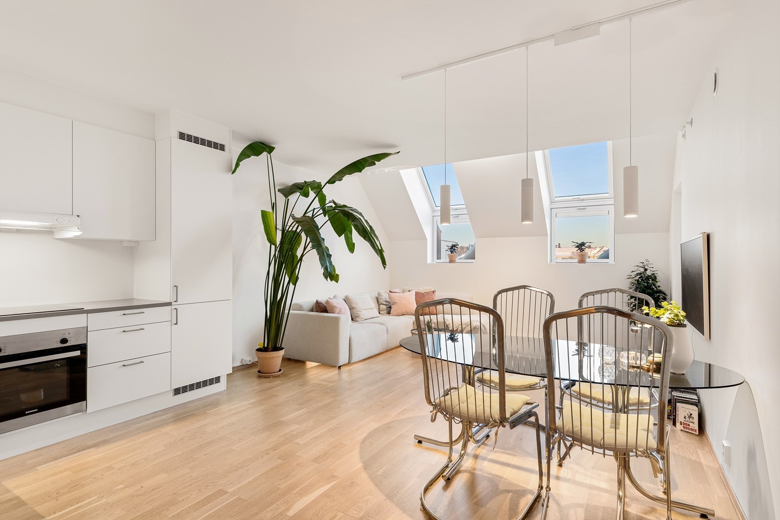 Moderne kjøkken med parkett på gulvet og malte, slette flater på vegger og tak. Kjøkkeninnredningen har glatte fronter og laminatbenkeplater, som gir et stilrent og lettstelt uttrykk. Galleribilde