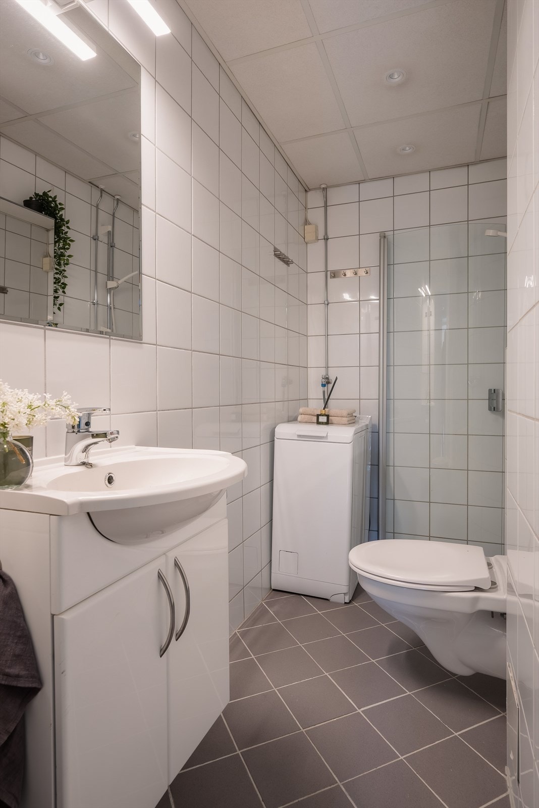 Flislagt bad med gulvvarme, downlights og opplegg for vaskemaskin Galleribilde