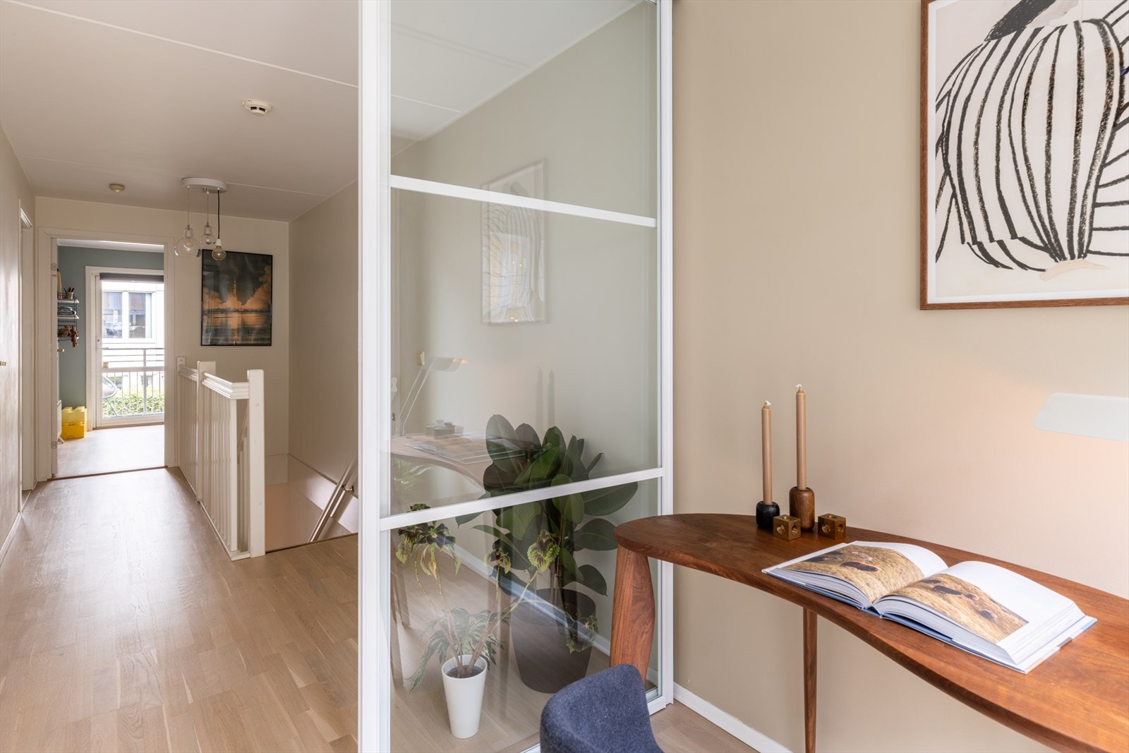En smart utnyttelse av plassen som gir en funksjonell arbeidsplass med skyvedører i glass som slipper lys inn i boligen/trappegangen men skjermer for lyd. Galleribilde