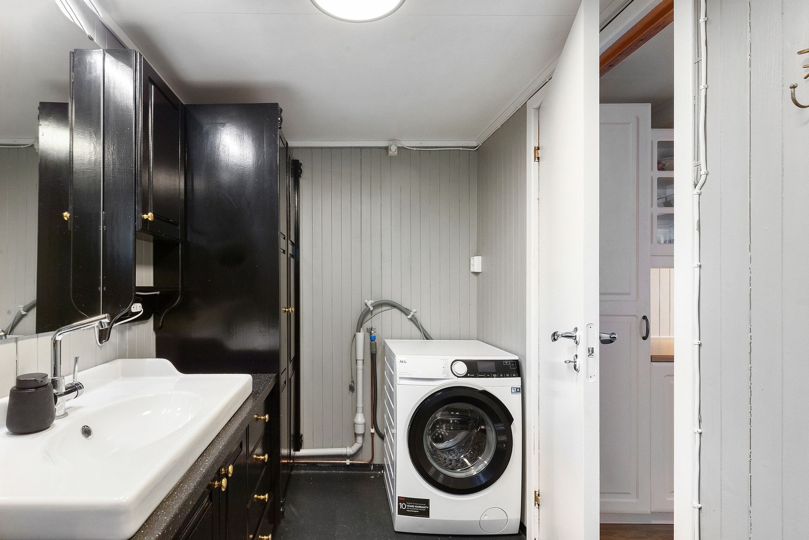 Badet er utstyrt med dusjkabinett, wc, opplegg for vaskemaskin, servant og servantskap. Galleribilde