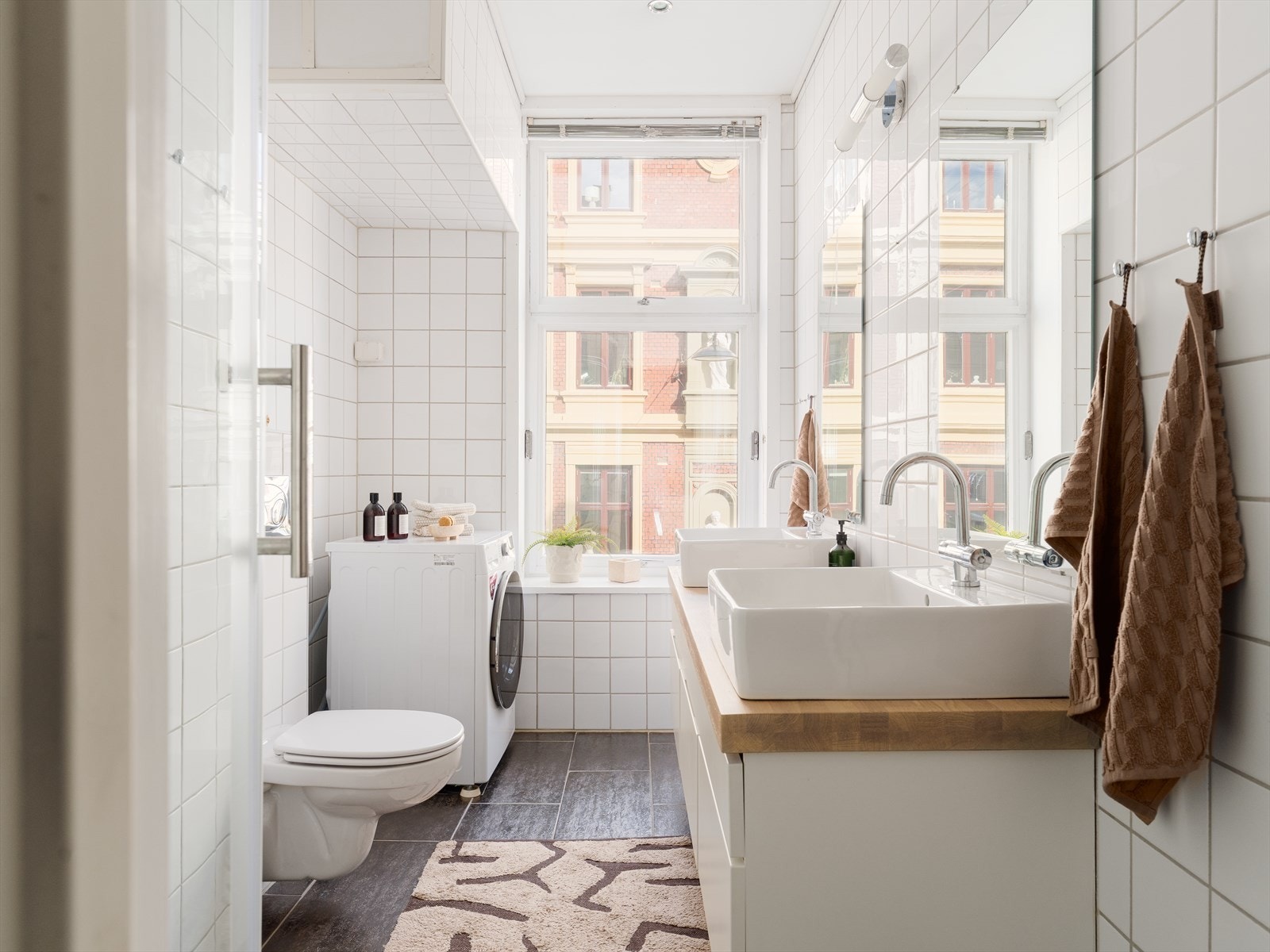 Badet er praktisk innredet med to servanter på en benkeplate i tre og god oppbevaring i underskap. Galleribilde