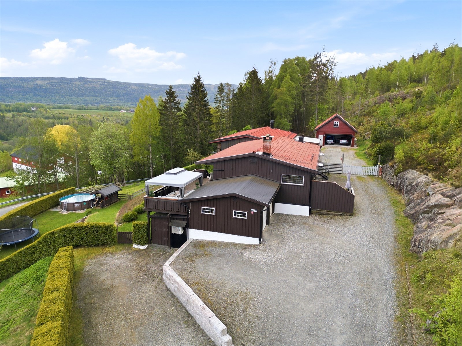 Store skogbruksarealer på baksiden av tomten og gruset adkomst med flere biloppstillingsplasser. Galleribilde