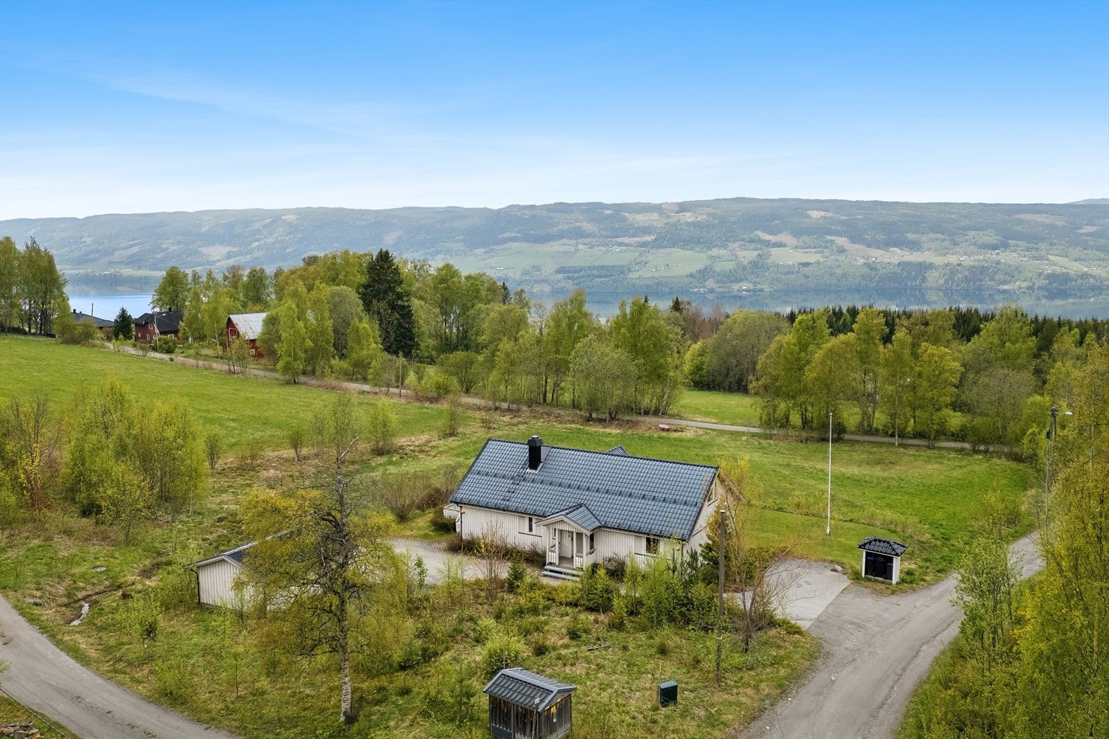 Fra eiendommen er det utsikt mot skogkledde åser og spredt bebyggelse. Galleribilde