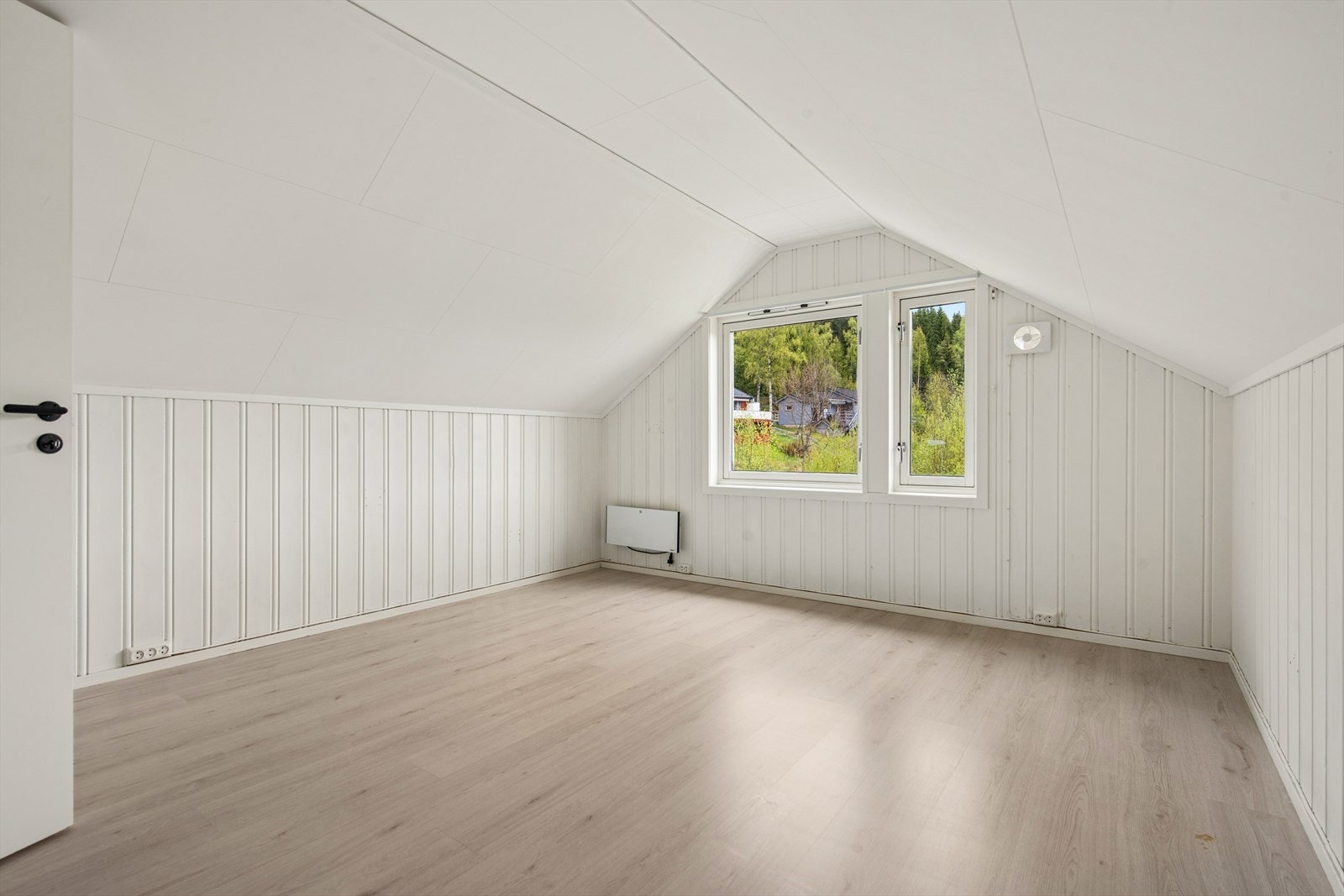 Lyst, innredet rom i andre etasje med panel på veggene og skråtak. Galleribilde