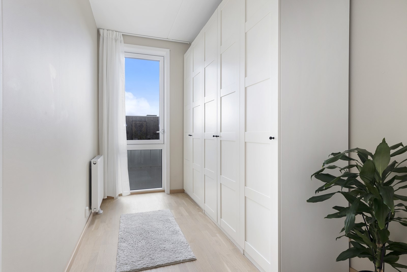 Rommet har en større etablert garderobeløsning og store vindusflater fra gulv til tak som bidrar til en luftig romfølelse. Galleribilde