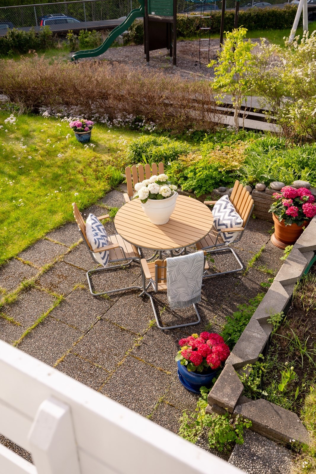 Flere flislagte heller skaper hyggelige soner i hagen, blant annet en lun og skjermet uteplass omkranset av beplantning. Galleribilde