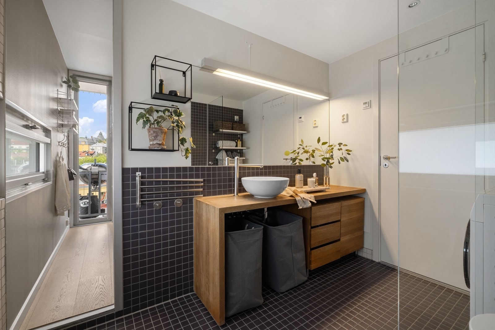Badet fremstår moderne og stilrent med flislagt gulv og vegger med delvis fliser og malte veggplater. Galleribilde