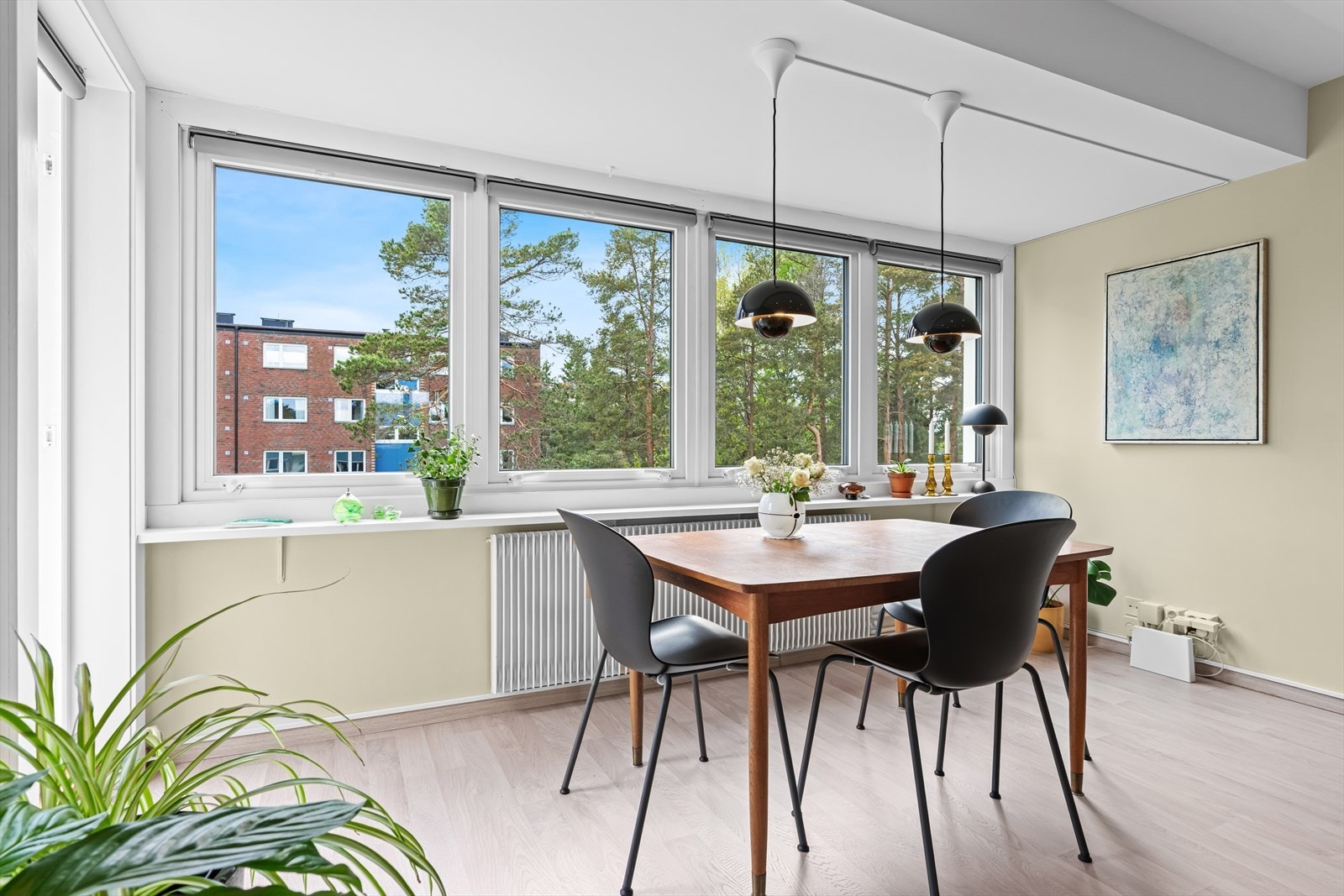 Utsikten går mot grøntarealet og furutrærne på eiendommen, med lekeplass synlig nedenfor. Galleribilde