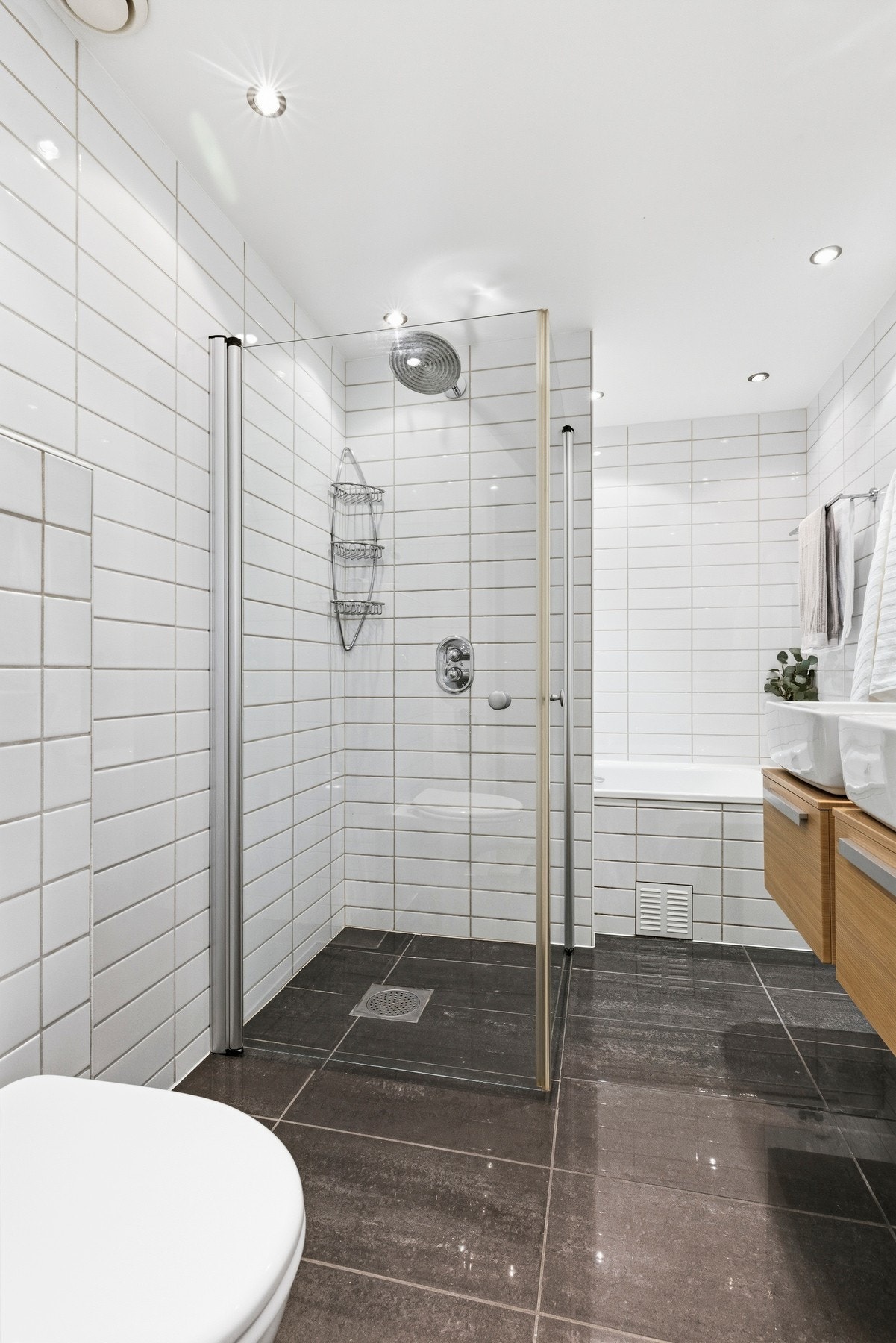 Badet er innredet med dobbel servant med underskap og overskap, vegghengt toalett, innmurt badekar, dusjløsning samt opplegg for vaskemaskin. Galleribilde