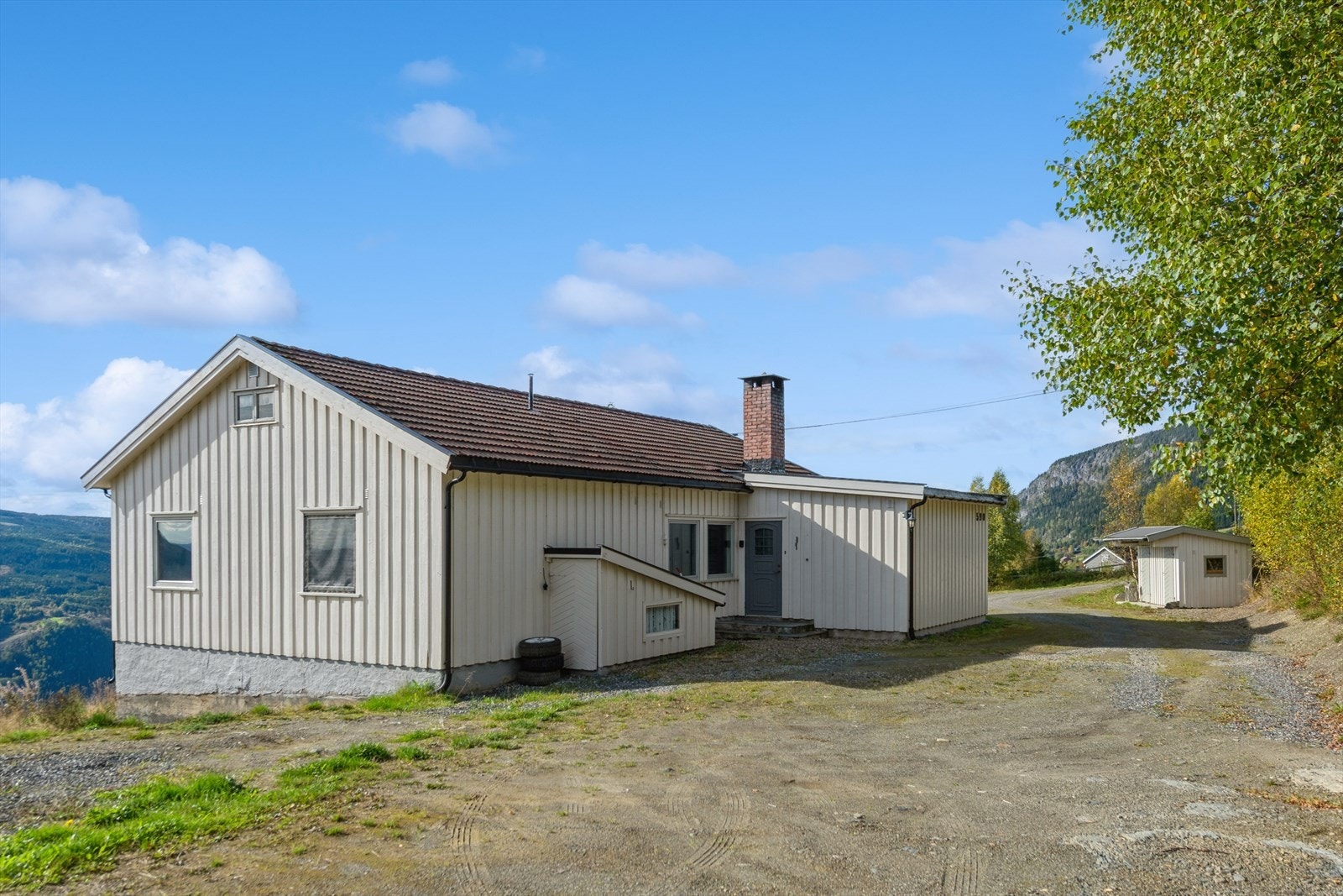 Bolighuset har stående trekledning og tak tekket med takstein Galleribilde