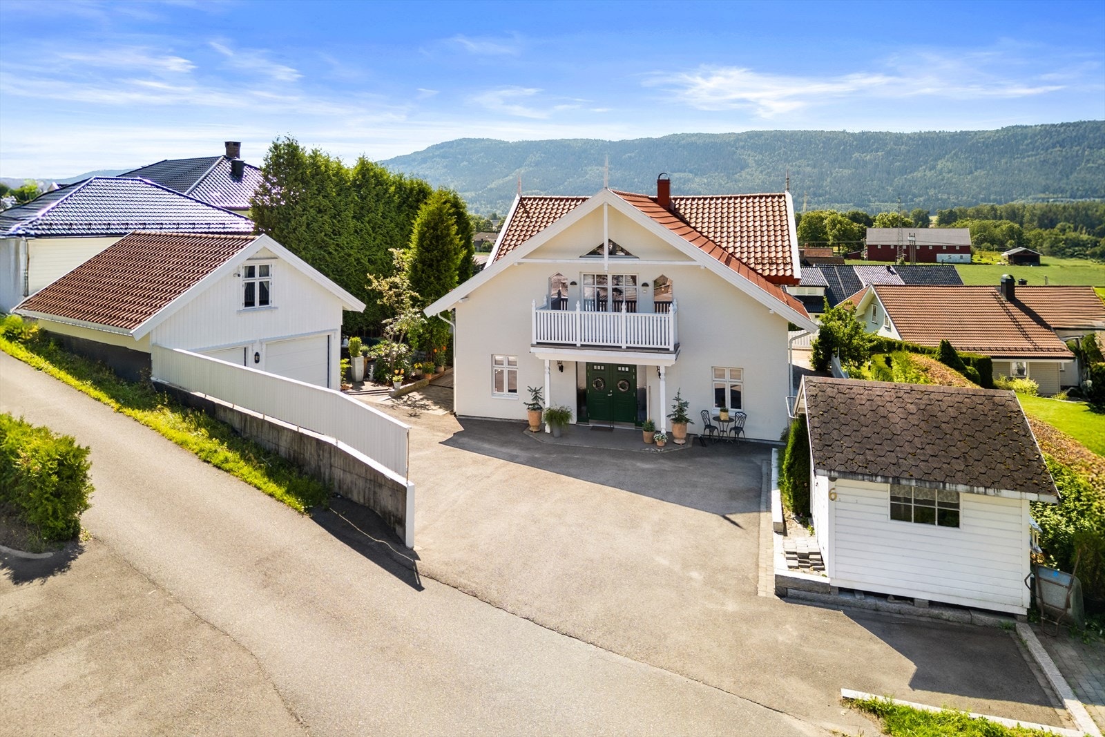 Stor asfaltert gårdsplass, pent omkranset med belegningsstein. Garasje har isolert og innredet loft for lagring Galleribilde