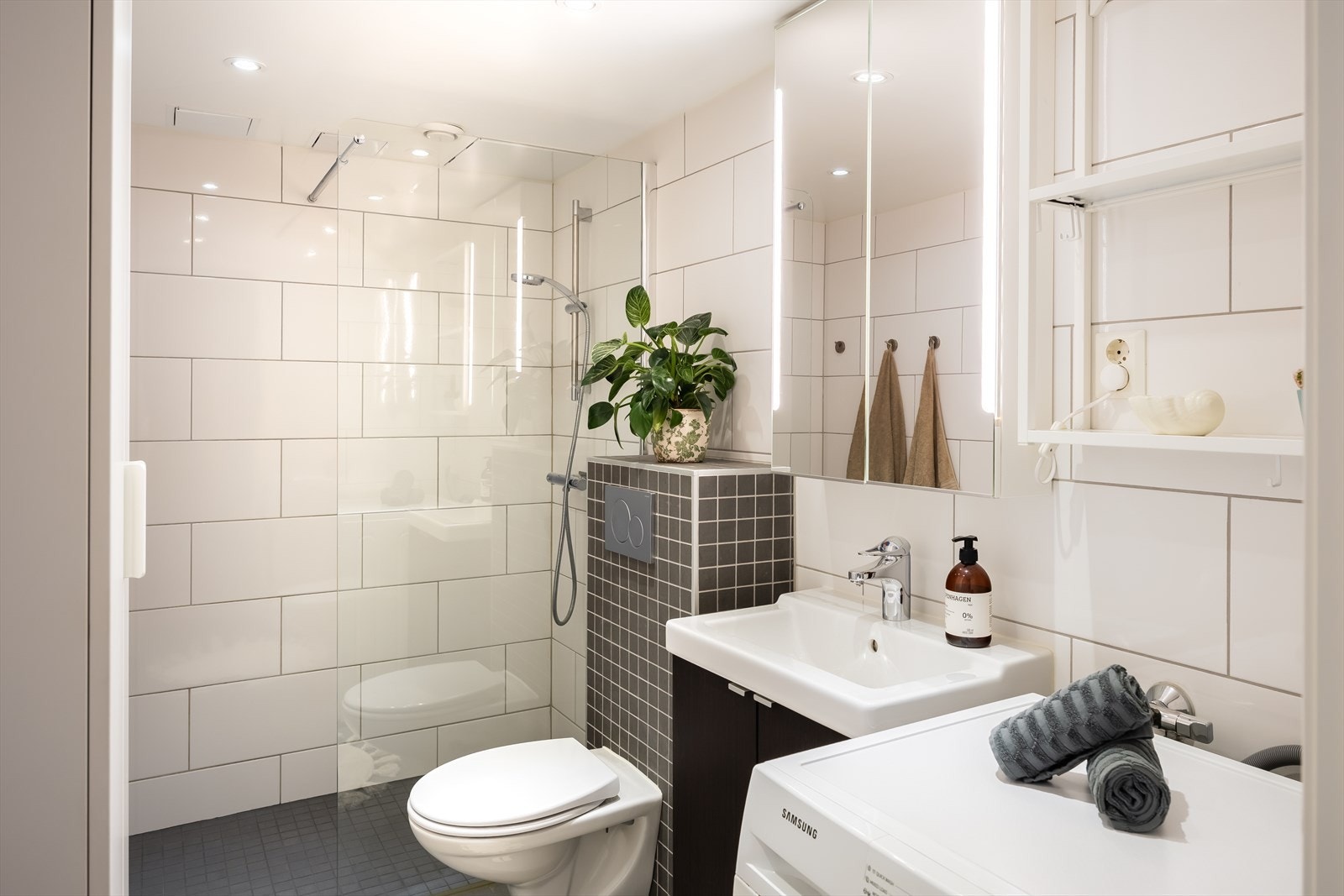 Badet ble oppgradert i 2013 og er pent flislagt. Badet innehar dusjsone, vegghengt toalett, servant, høyskap, speilskap med integrert belysning og opplegg for vaskemaskin. Galleribilde