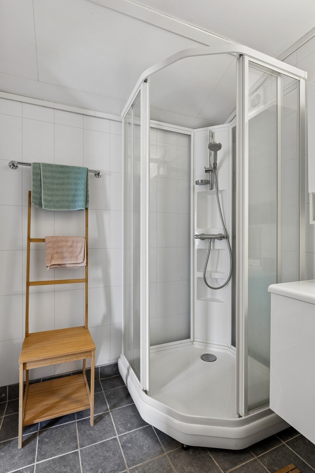 Badet har flislagt gulv med varmekabler, dusjkabinett, toalett og baderomsplater på veggene. Galleribilde
