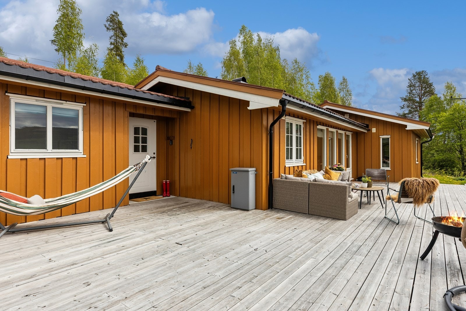 En stor treterrasse strekker seg langs fasaden og gir rikelig med plass til flere sittegrupper. Terrassen er ikke byggemeldt ihht. tegninger. Galleribilde