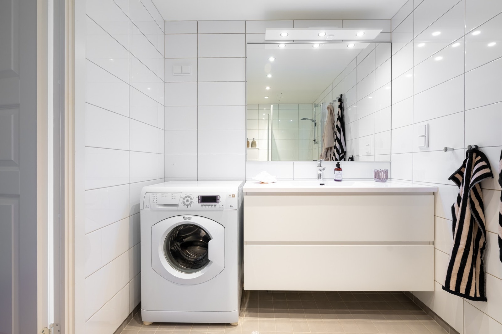 Badet er av god størrelse og er utstyrt med stor innredning med to skuffer og nedfelt servant, speil med belysning over, vegghengt toalett og dusjhjørne med innfellbare dusjdører. Galleribilde