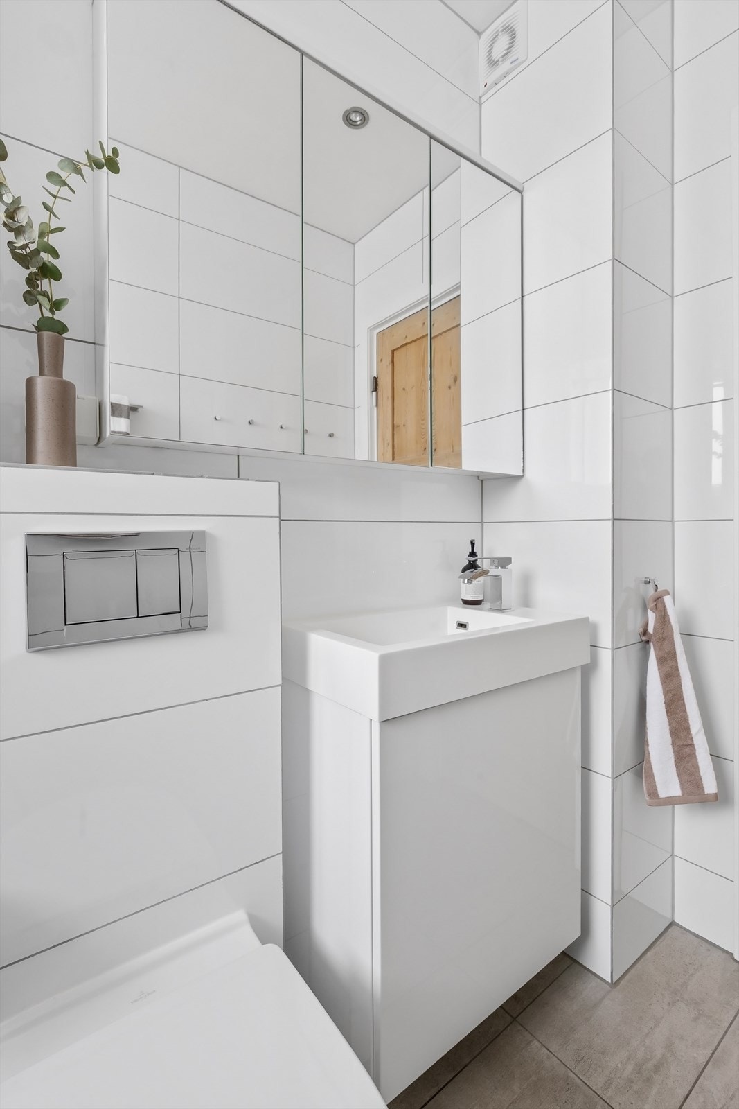 Badet har stort dusjhjørne, vegghengt toalett og veggskap med speilfronter Galleribilde