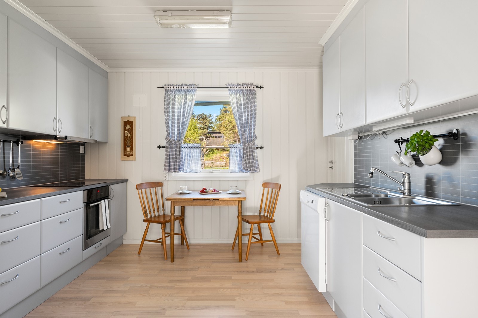 Kjøkkenet er utstyrt med platetopp, stekeovn, kjøleskap og en kjøkkenventilator med avtrekk ut. Det er dessuten plass til en mindre spisegruppe ved vinduet. Galleribilde