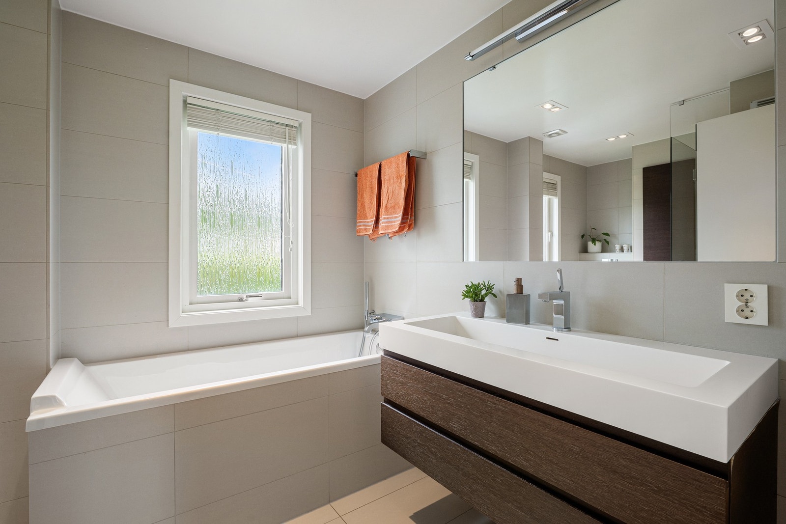 Badet er innredet med servantskap, stort speil, innfliset badekar og gode løsninger for både hverdag og familieliv. Galleribilde
